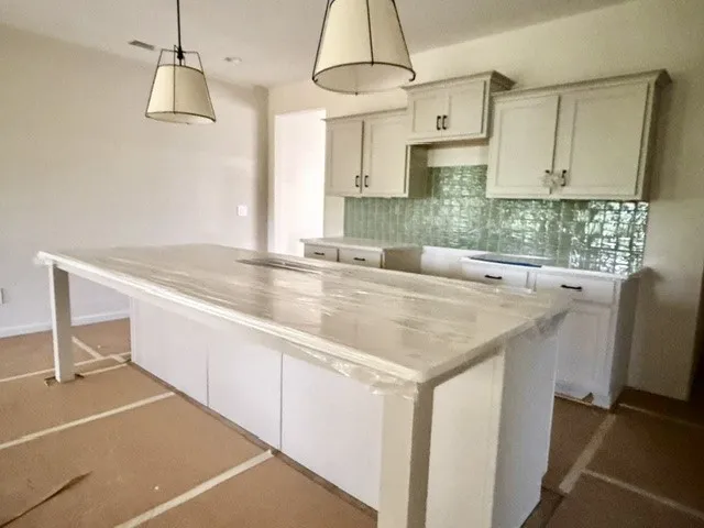 A spacious, naturally illuminated kitchen features a large island and ample cabinetry, ready for culinary endeavors.