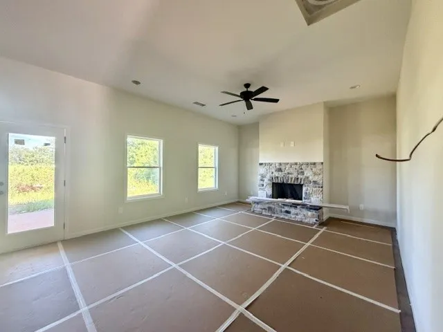 A spacious living area features a grand stone fireplace and abundant natural light.
