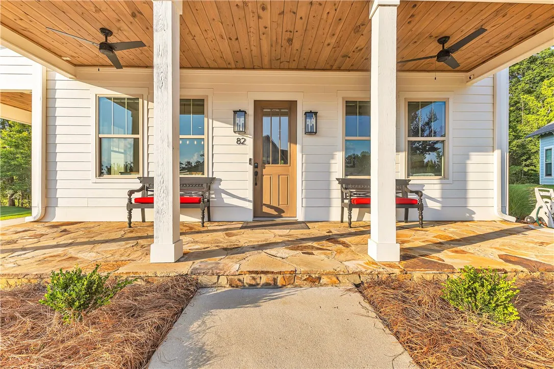 A welcoming stone-tiled porch, shaded by a wood-planked ceiling, offers a tranquil outdoor retreat.