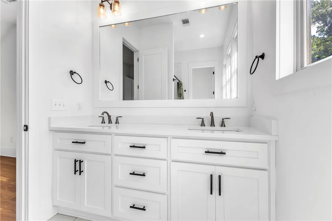 A well-appointed primary bathroom vanity features dual sinks and ample storage beneath a spacious mirror.