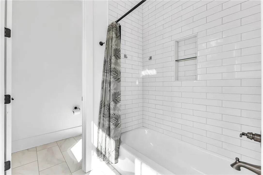 A pristine bath, accented by classic subway tile and practical recessed shelving, offers a refreshing escape.