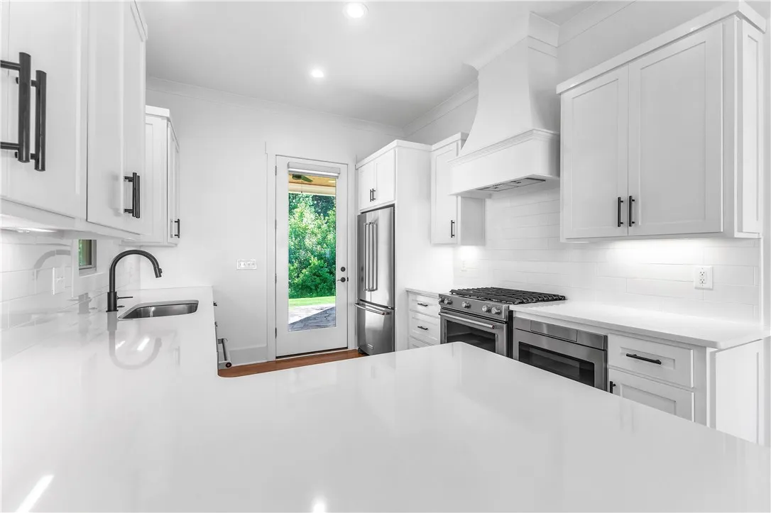 A brilliant white kitchen, accented with matte black hardware, offers a sleek and functional cooking space.