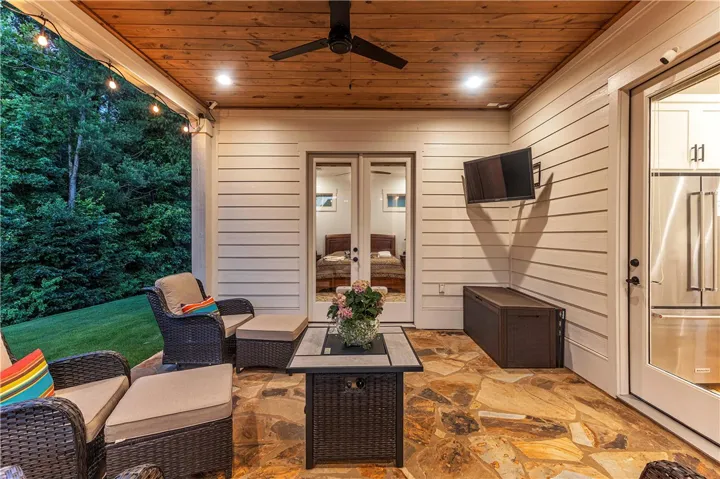 An inviting covered patio featuring flagstone flooring, a wooden plank ceiling, and string lights offers an ideal setting for relaxation.