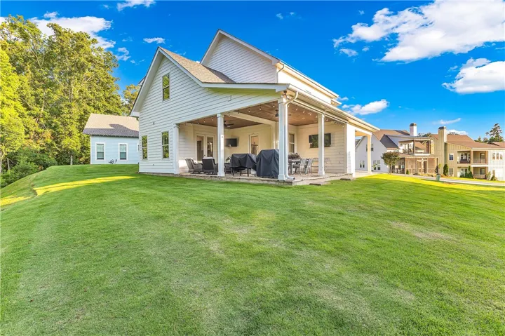 A spacious covered patio with white columns extends from a crisp white siding home, perfect for outdoor entertaining.