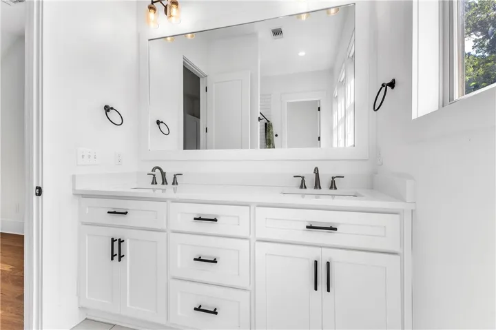 A well-appointed primary bathroom vanity features dual sinks and ample storage beneath a spacious mirror.