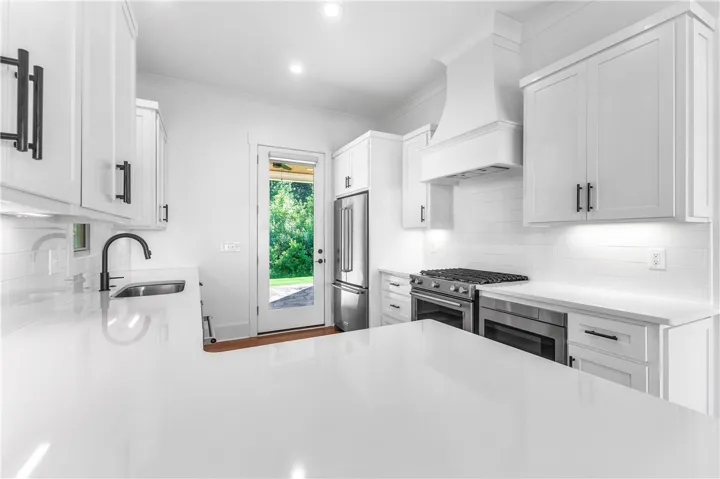 A brilliant white kitchen, accented with matte black hardware, offers a sleek and functional cooking space.