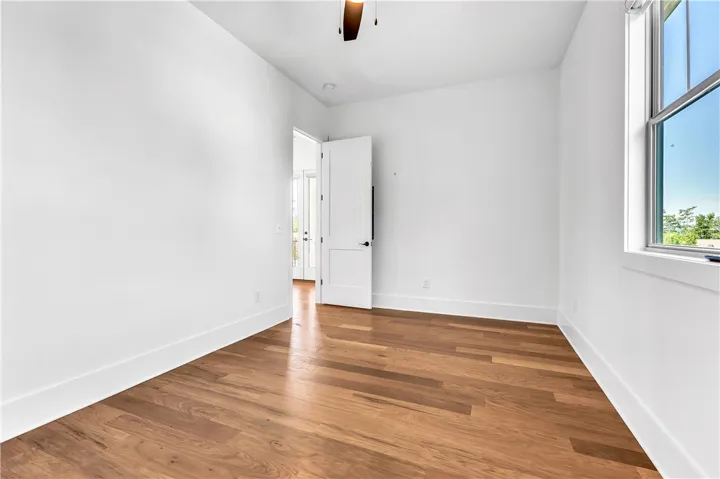 Hardwood floors and a wide window create a bright, inviting bedroom space.