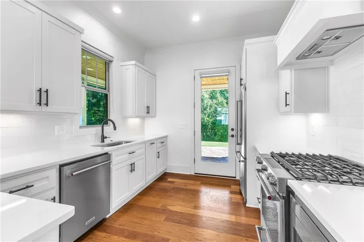 A pristine kitchen features sleek appliances, abundant cabinetry, and a bright view to the outdoors.