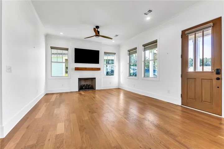 Refined wood flooring extends throughout this naturally illuminated living space, centered by a charming fireplace.