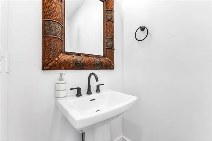 A striking mirror with an intricately woven frame elevates this compact bathroom's visual appeal.