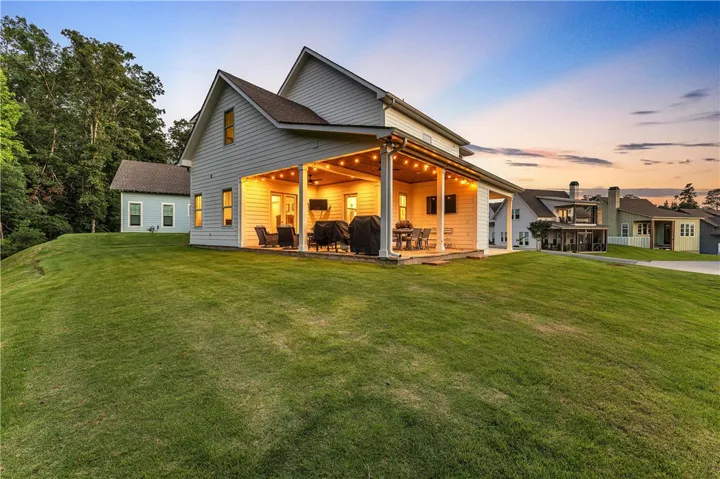A spacious, illuminated rear patio extends entertaining to a verdant backyard, perfect for twilight gatherings.
