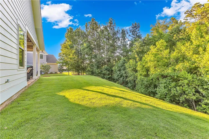 A verdant backyard with mature trees and a shaded porch offers peaceful outdoor living.
