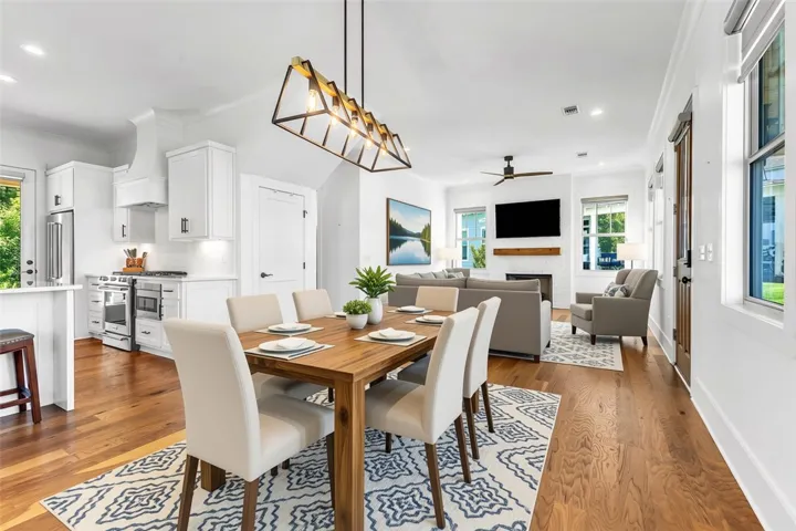 An open concept design seamlessly connects the dining area, chef's kitchen, and a cozy living space with a fireplace.