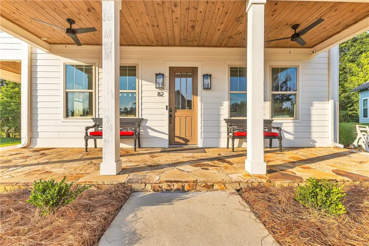 A welcoming stone-tiled porch, shaded by a wood-planked ceiling, offers a tranquil outdoor retreat.