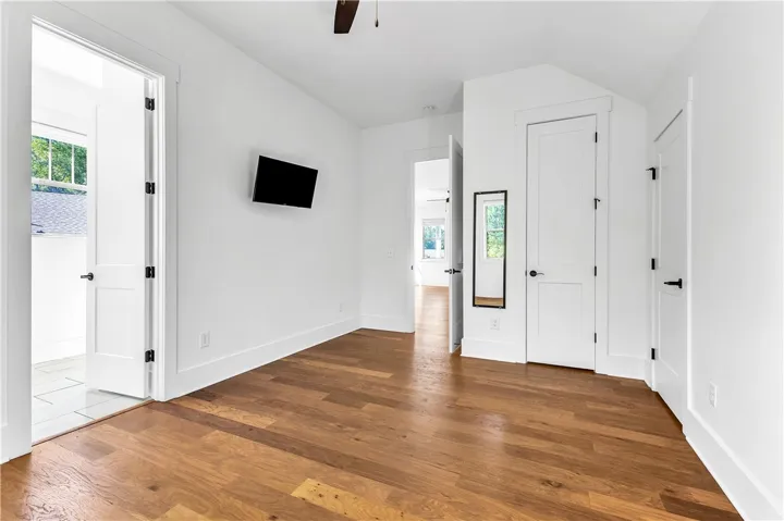 Rich hardwood flooring creates a welcoming atmosphere in this generously sized, well-lit bedroom.