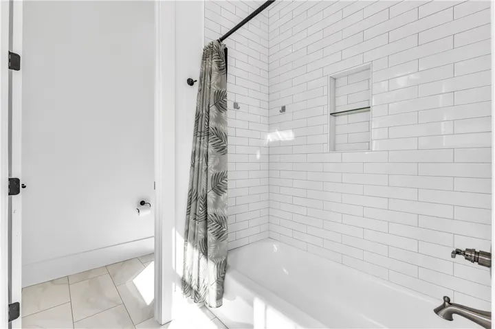 A pristine bath, accented by classic subway tile and practical recessed shelving, offers a refreshing escape.