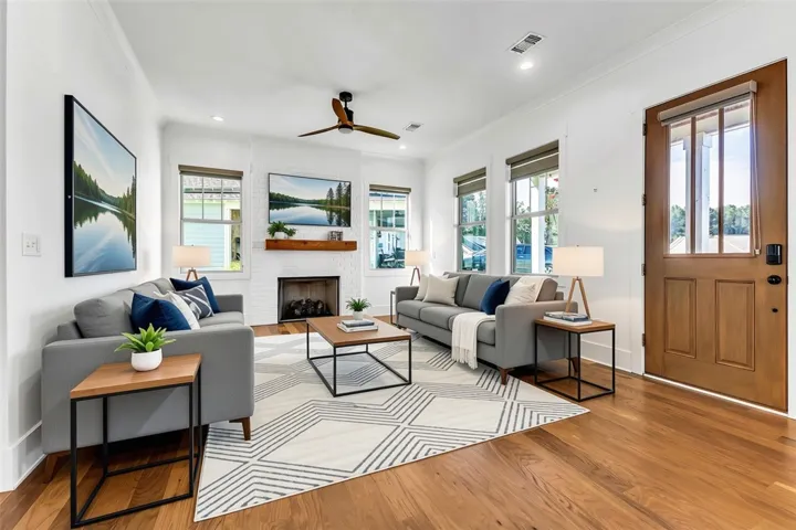 Warm hardwood floors and a white brick fireplace invite gatherings in this naturally illuminated living room.