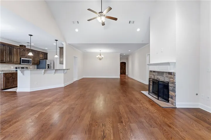 Vast hardwood flooring spans an open-concept layout, connecting the chef's kitchen to a cozy fireplace.