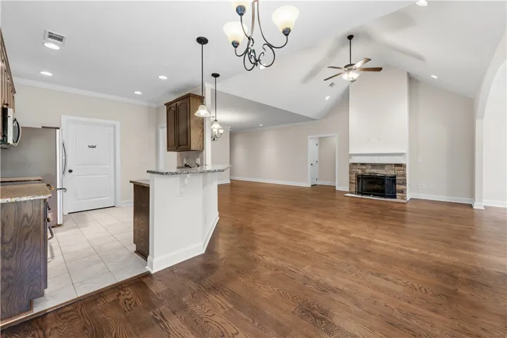 An open floorplan seamlessly connects the kitchen to a spacious living area featuring a vaulted ceiling and stone fireplace.
