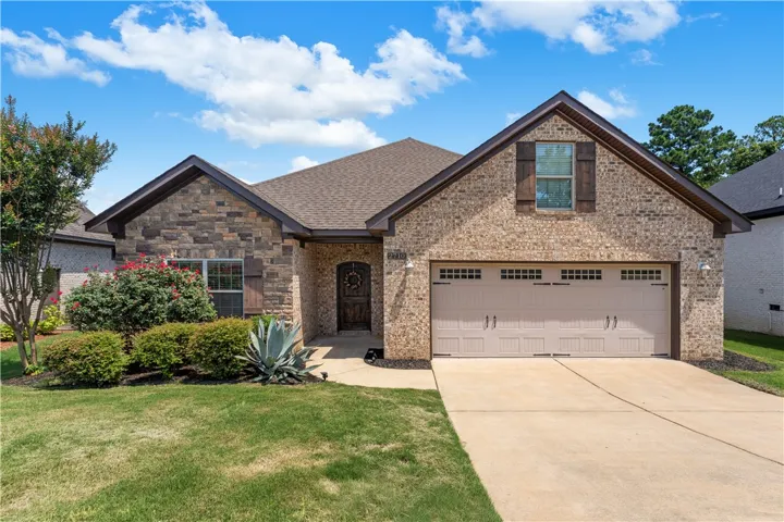 Crafted from rich stone and brick, this home features a warm wood front door and an integrated two-car garage.
