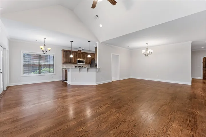 An open-concept living space with lustrous hardwood flooring, cathedral ceilings, and a well-appointed kitchen.