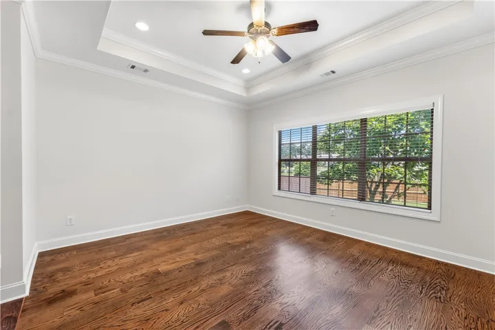 Rich hardwood floors complement tray ceilings in this versatile primary bedroom or home office.