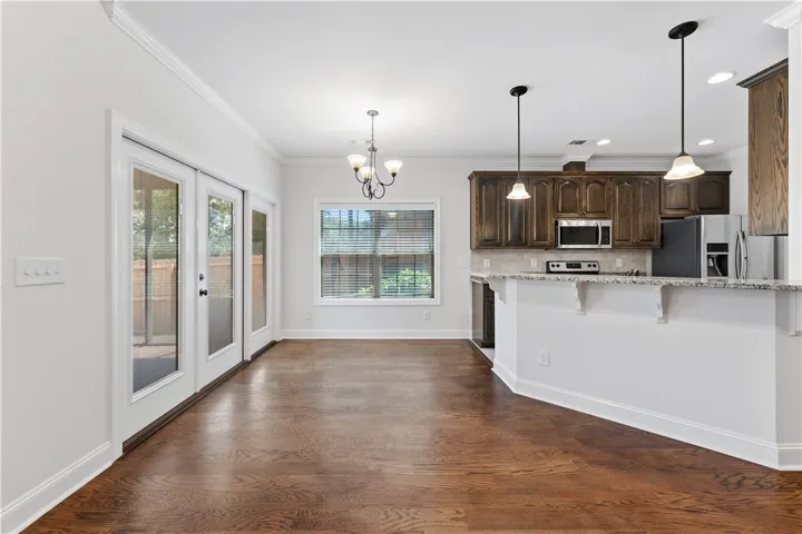 Rich hardwood floors flow through this open-concept space, connecting the kitchen with ample light from glass-paneled doors.