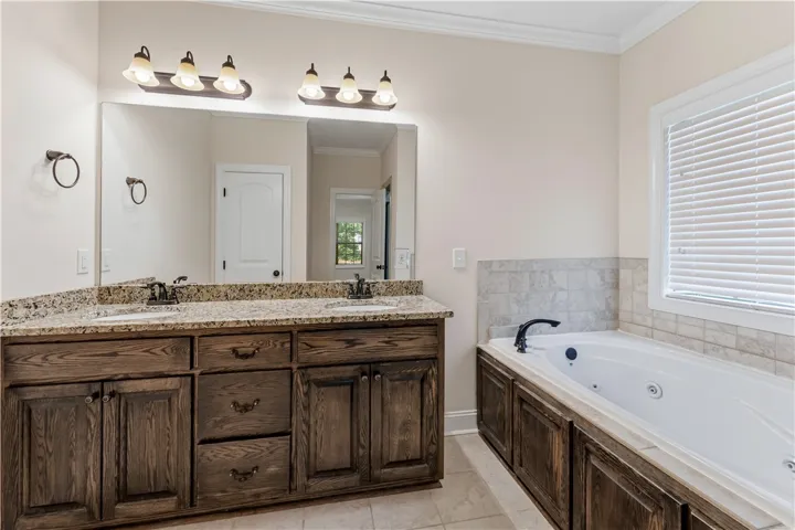 Granite counters provide ample space in this well-appointed bathroom featuring a jetted tub.