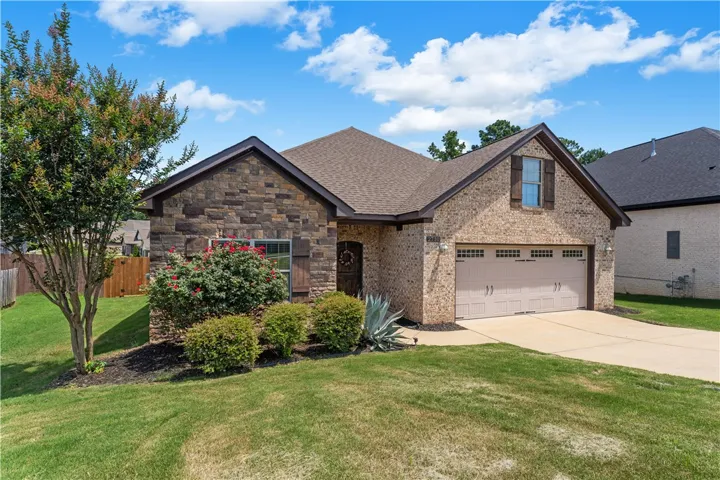 A classic brick and stone facade welcomes with neatly trimmed shrubs and mature landscaping.