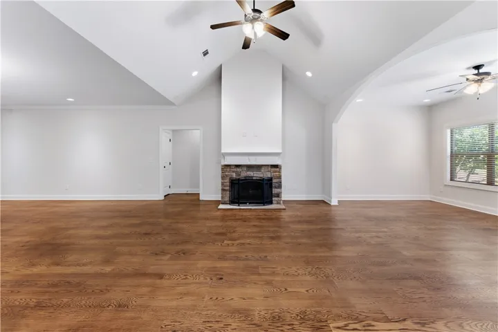 A spacious living room features vaulted ceilings, hardwood floors, and a stone-faced fireplace, ready for gatherings.