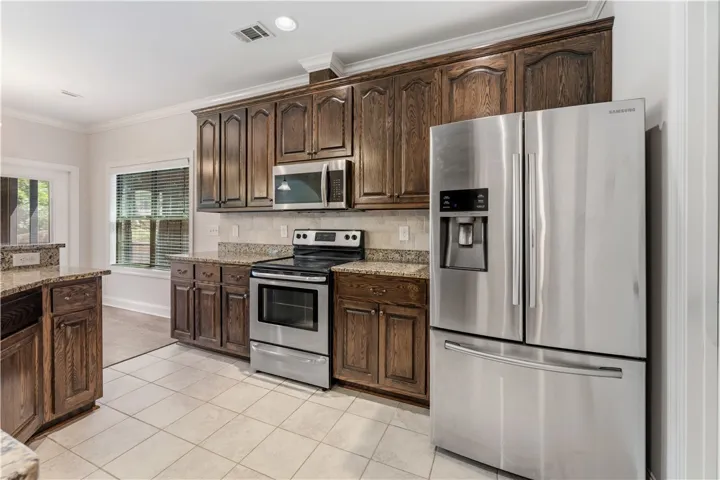 A well-appointed kitchen features rich wood cabinetry, granite countertops, and modern stainless steel appliances.