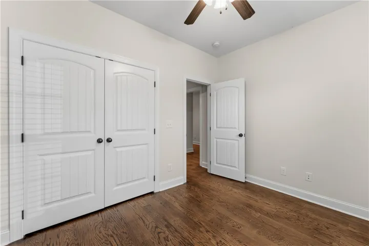 Rich hardwood floors complement the clean, bright white walls of this inviting bedroom space.