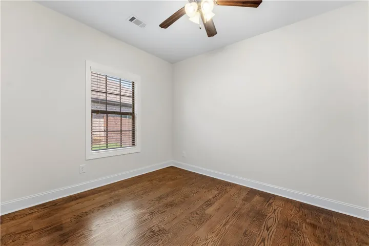 Hardwood floors and a bright window with blinds enhance this tranquil room.