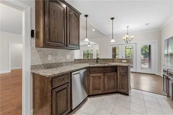 A well-appointed kitchen features wood cabinetry, granite counters, and a tiled backsplash, leading to an adjoining dining area.