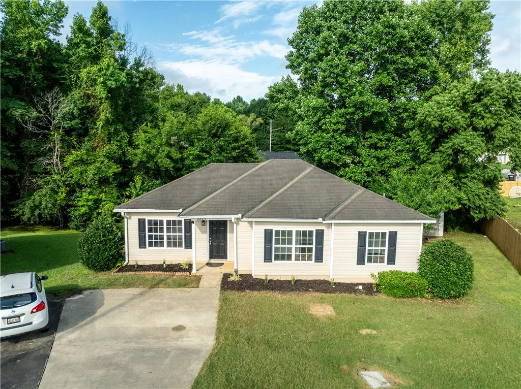 A classic ranch home nestled among abundant greenery with a fenced backyard.