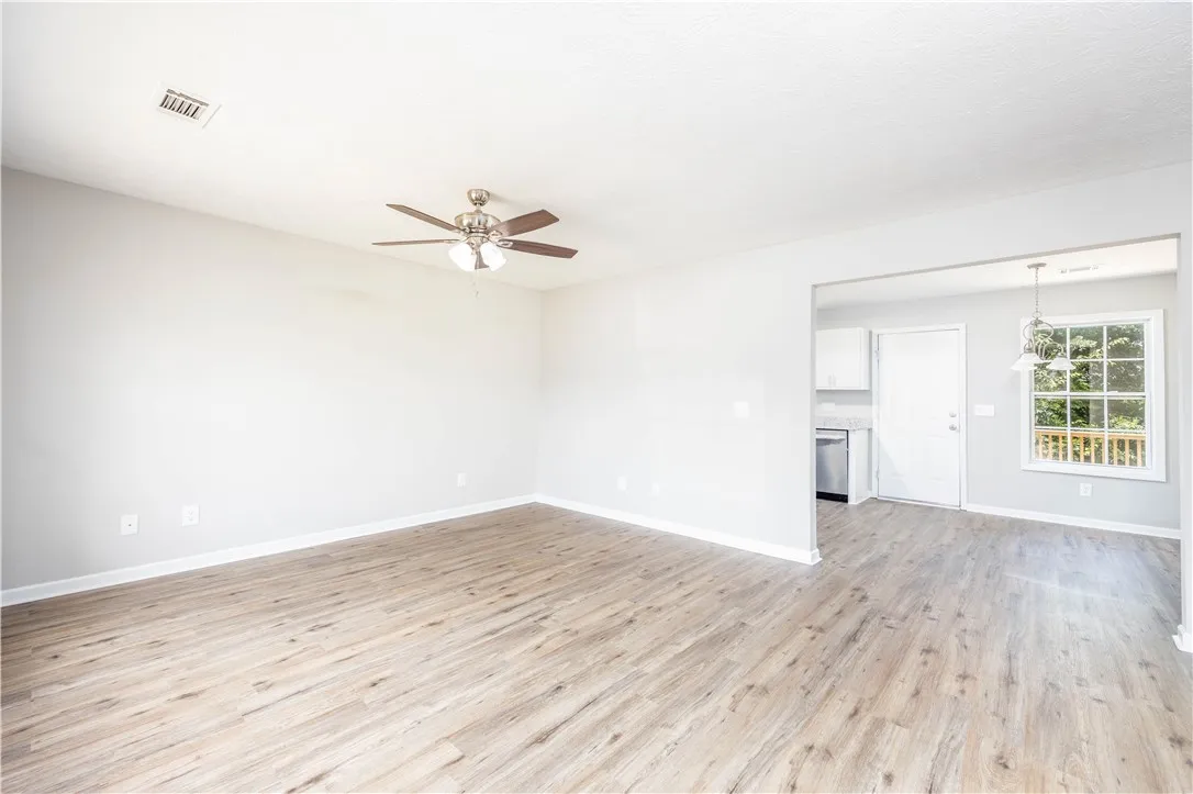 An open floorplan living area features light wood flooring and a kitchen pass-through.
