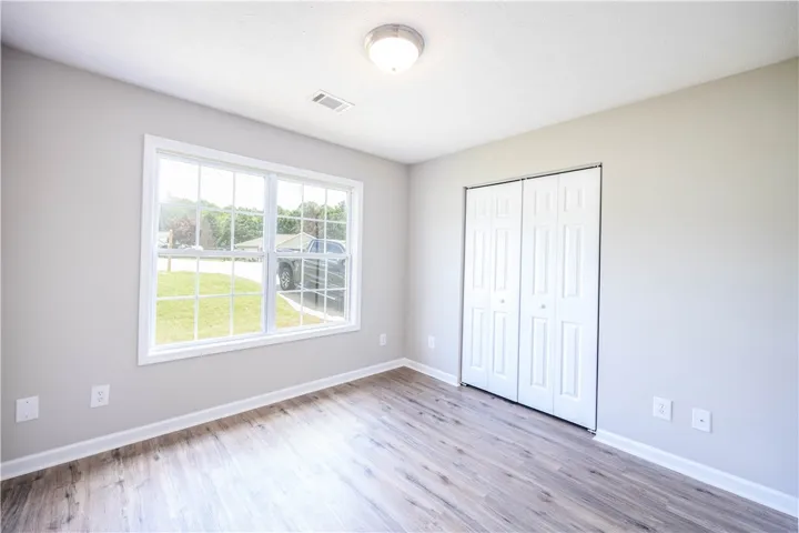 Sun-filled room featuring durable wood-like flooring and ample closet space.