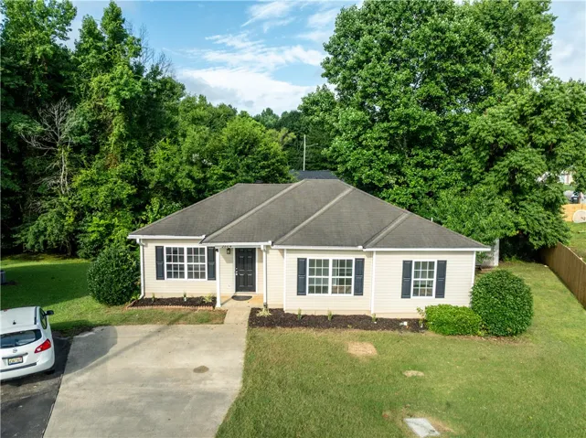 A classic ranch home nestled among abundant greenery with a fenced backyard.