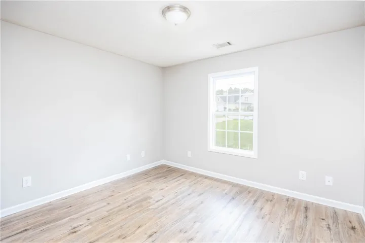 Naturally illuminated bedroom features durable plank flooring and a bright window overlooking the neighborhood.