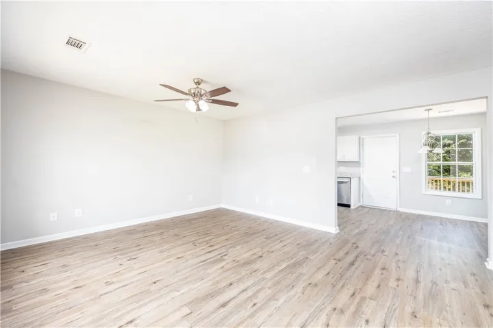 An open floorplan living area features light wood flooring and a kitchen pass-through.
