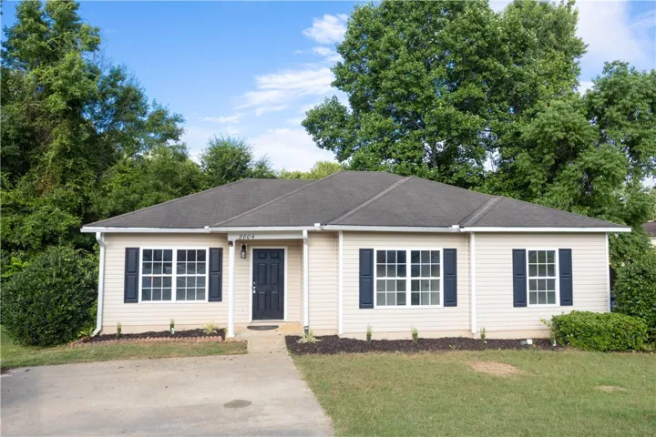 A charming single-story residence with a pristine lawn, complemented by mature trees providing natural privacy.