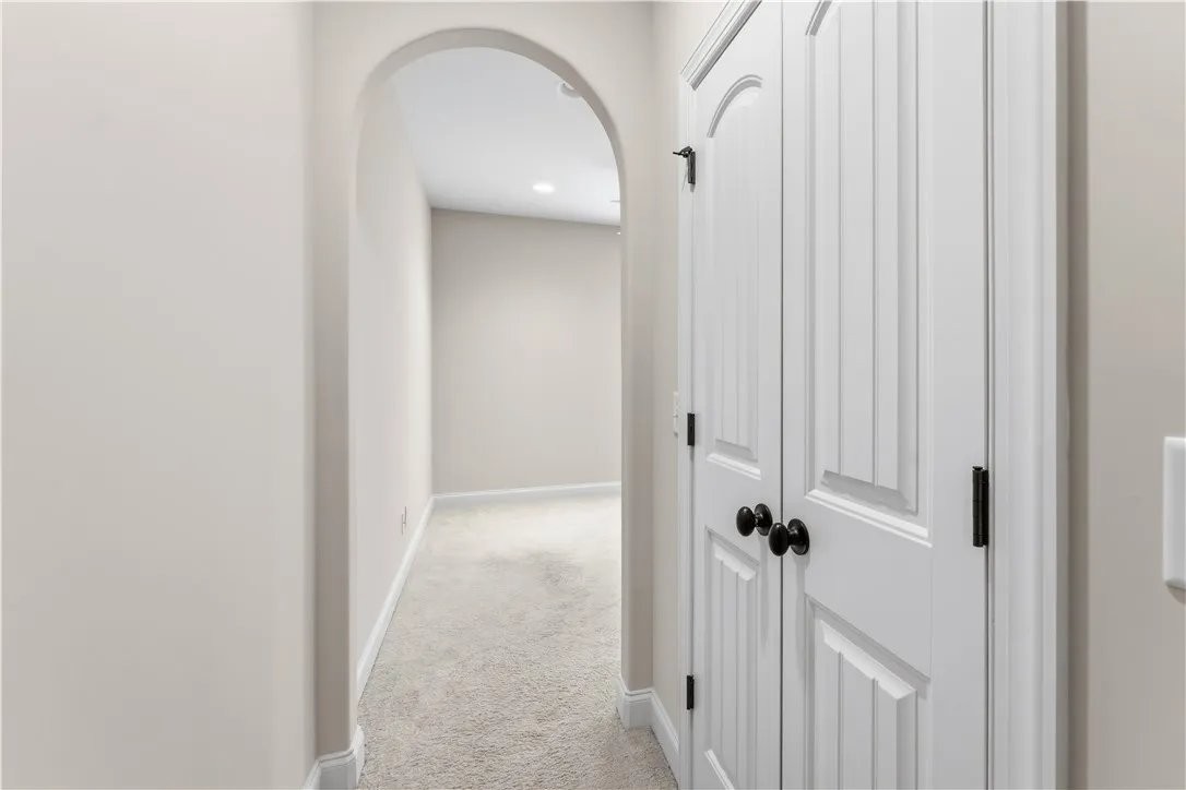 A well-lit interior hallway features an elegant arched entryway and a closed storage closet.
