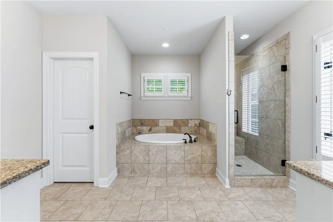 Unwind in a luxurious primary bathroom featuring a spacious soaking tub and a sleek, tiled walk-in shower.