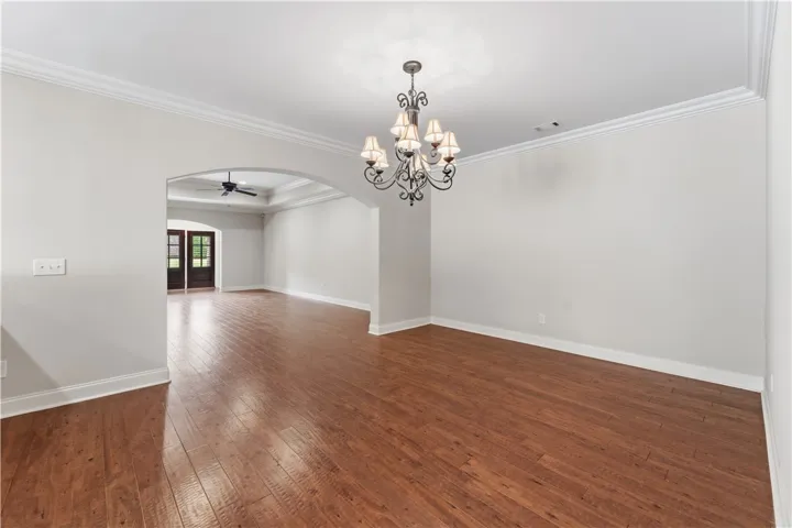Elegant crown molding accents the formal dining space, complete with polished hardwood flooring and an inviting archway.