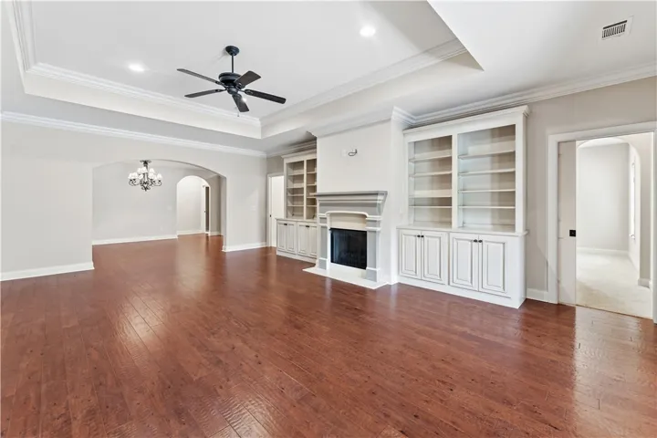Hardwood floors and built-in shelving complement this spacious living area, highlighted by a cozy fireplace.