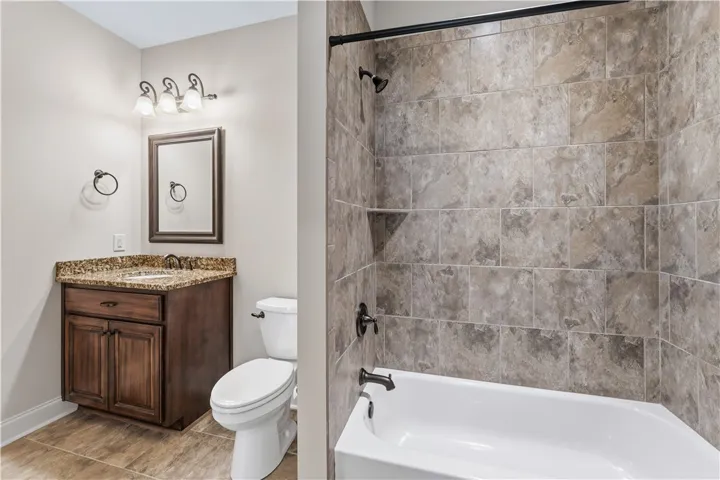 A well-appointed bathroom features a dark wood vanity with granite counters and a tiled shower/tub combination.