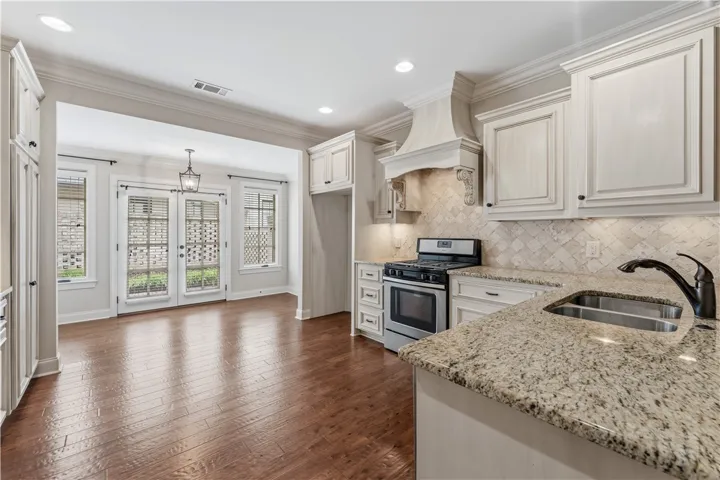Gleaming hardwood floors and ample counter space define this bright kitchen, leading to charming French doors.
