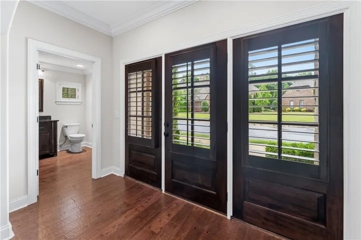 Rich hardwood floors welcome you into this inviting entry, offering privacy with elegant window shutters.