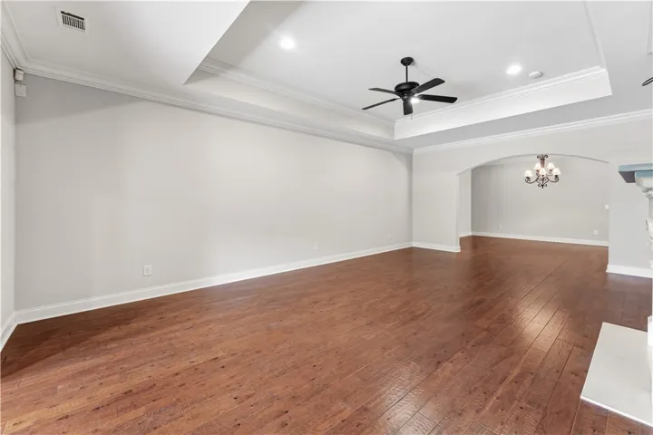 Rich hardwood floors flow through this spacious interior, crowned with a tray ceiling and a classic chandelier.