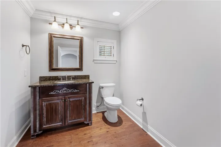 A dark wood vanity with granite counters and rich hardwood floors defines this tasteful guest bath.
